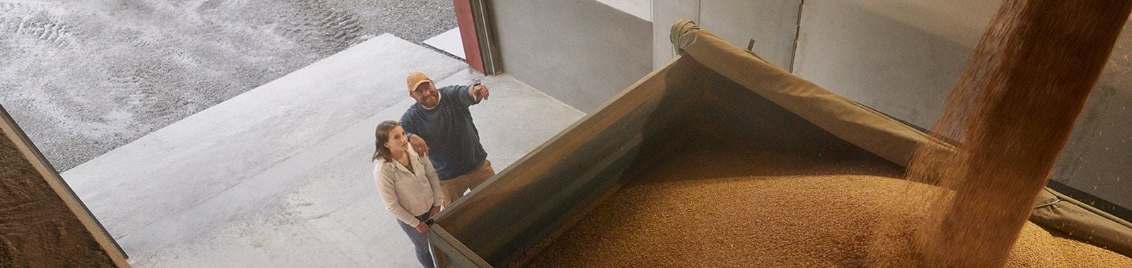 Farmer and daughter watching wheat load 